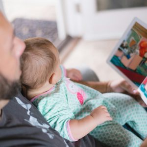 An adult reads an illustrated book to a baby